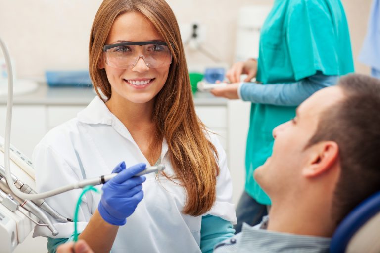 Female Dentist Examining And Working On Young Male Patient.dentist's Office.